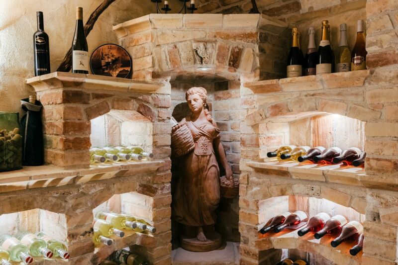 Gemauerte Weinnischen im Weinkeller mit Weißwein- und Rosé-Flaschen