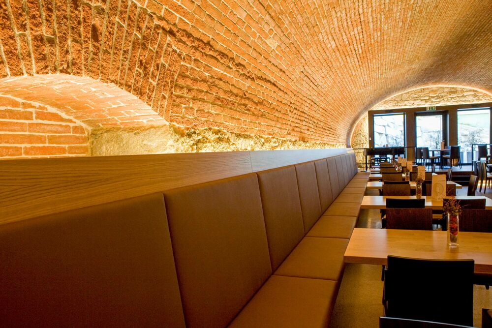 Indirekt beleuchtete Nischen mit warmen Licht als Ablagefläche im Restaurant mit Tonnengewölbe