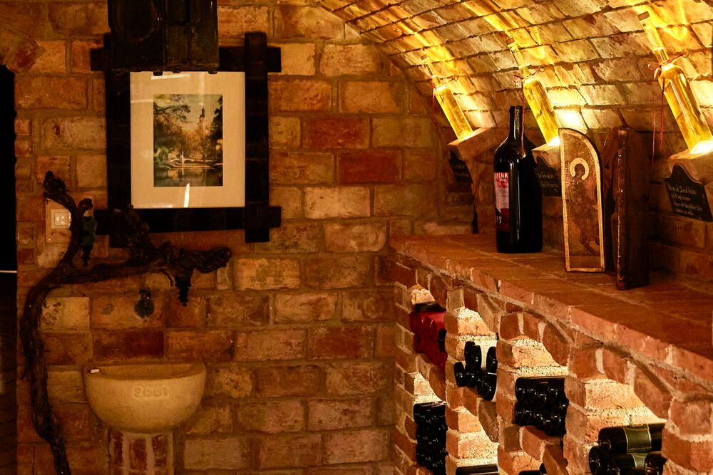 Weinkeller mit Tonnengewölbe, gemauerten Weinnischen und dezentem Steinbecken
