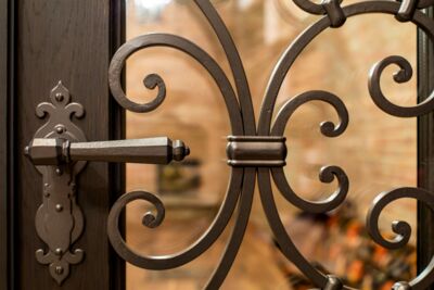Tür mit handgeschmiedetem Türgriff und dekorativem Gitter im Weinkeller